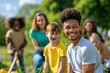 © Jane_S - Group of teenagers and children smiling and gardening together in a sunny outdoor setting.