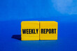 © Emre Akkoyun - Weekly report message written on yellow wooden cubes with blue background. Conceptual weekly report symbol. Copy space.