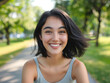 © Irina B - Smiling young woman with dark hair in a green park on a sunny day.
