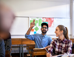 Leinwandbilder - Male person, hand raised and education at university, college or school in classroom for question. Student, group and confident with textbook on desk for exam, project or tutorial in learning english
