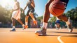 © inthasone - A young male basketball player dribbling the ball on an outdoor basketball court in action.