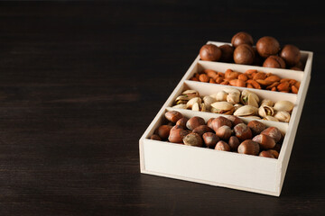 Wall Mural - Wooden box with different nuts on a dark background