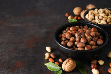 Wall Mural - Different types of nuts in black bowls on a dark background