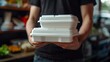 © ifoto - Close up of a man's hand holding a white polystyrene take-out food box with two stacked on top