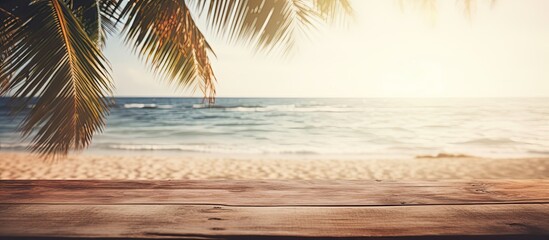 Poster - Blur tropical beach with bokeh sun light wave and palm tree on copy space empty old wood table abstract background Product presentation in nature Vintage tone filter effect color style