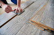 © anatoliy_gleb - Close up of male worker using metal construction ruler and pen while drawing line on laminate flooring board. Man preparing laminate plank for floor installation in apartment under renovation.