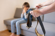 © kittyfly - wide leather belt in female parent's hand threatens misbehaving teenage boy sitting on couch, Parenting struggles