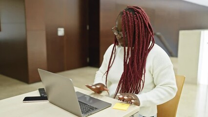 Sticker - Black woman with braids using laptop in modern office