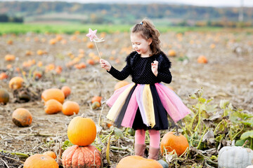little girl wearing halloween witch costume on pumpkin patch
