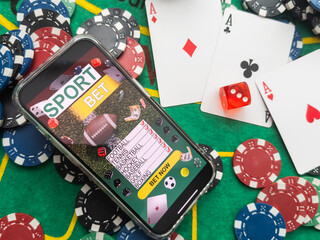 Wall Mural - Smartphone with poker table on screen, playing cards and chip cards on poker table. Online casino.