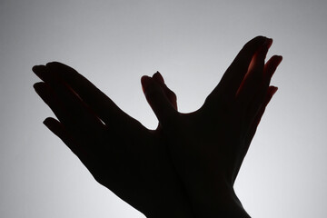 Wall Mural - Shadow puppet. Woman making hand gesture like bird on grey background, closeup