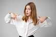 © fotofabrika - Young businesswoman standing against gray background and pointing her finger to copy space