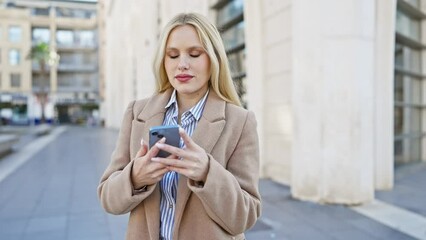 Poster - Attractive young woman using smartphone on city street while standing outdoors in urban surroundings.