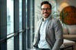 © Lucija - confident smiling businessman in glasses standing at modern office