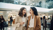© dvoevnore - Two smiling young women shopping at mall, carrying shopping bags