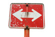 © Rattanathip - Weathered red roadside sign with dual arrows pointing left and right, symbolizing choice, decision, and directionality.