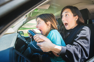 Mother and son behind the wheel of the vehicle and speed face. Transportation and family.