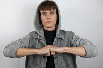 Young man with a denim jacket and hood on, putting his fists together