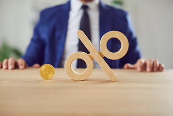 Close up shot of a bitcoin coin placed next to a percent sign, financial growth and dividends in cryptocurrency trading. Digital money market and the potential profit for businessman.