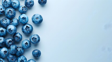 Wall Mural - Blueberries scattered on light blue background. Flat lay composition with copy space. Healthy eating and fruit concept for design and print
