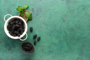 Wall Mural - Colander and bowl with fresh blackberries on green background