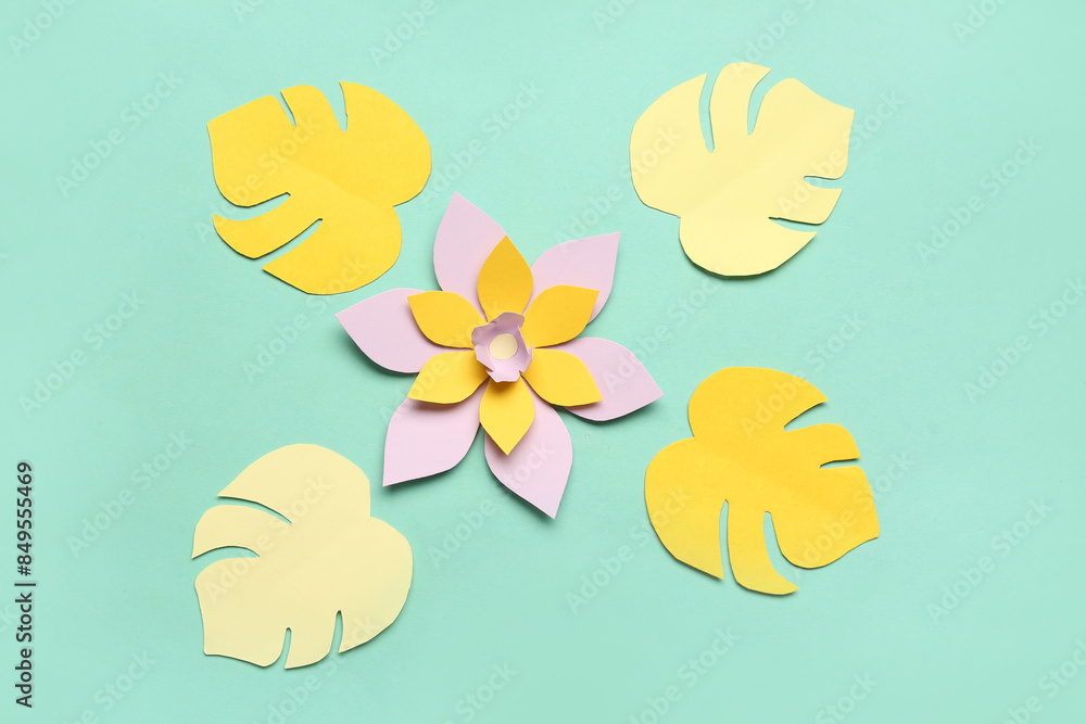Colorful origami flower with leaves on green background