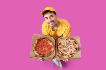 Sticker - Handsome tattooed young man with boxes of tasty pizza sitting on purple background