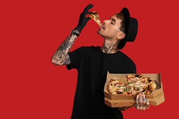 Sticker - Handsome tattooed young man eating tasty pizza on red background