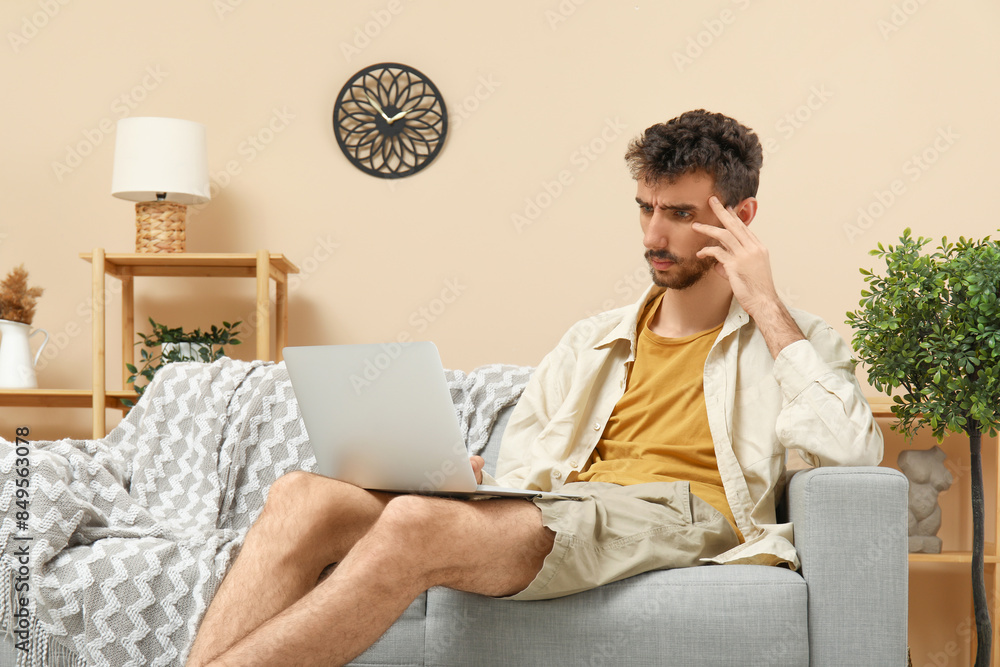 Handsome man using laptop on sofa at home