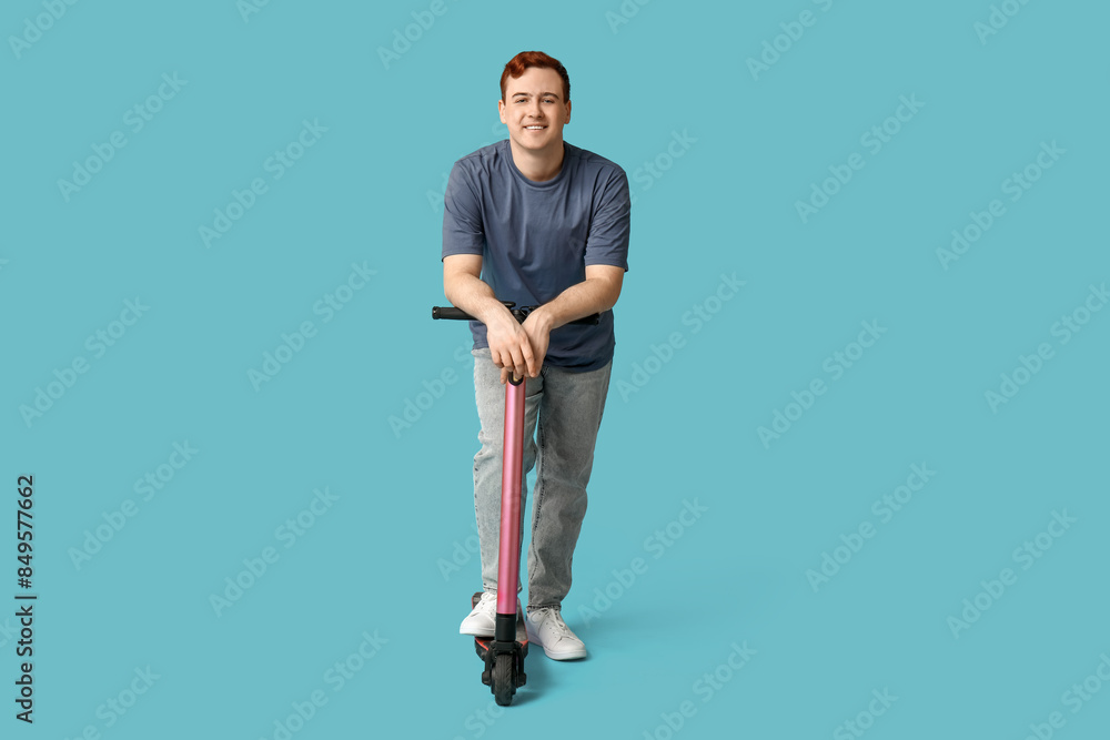 Young man with modern electric kick scooter on blue background