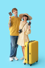 Wall Mural - Couple of young tourists with passports and suitcase on blue background