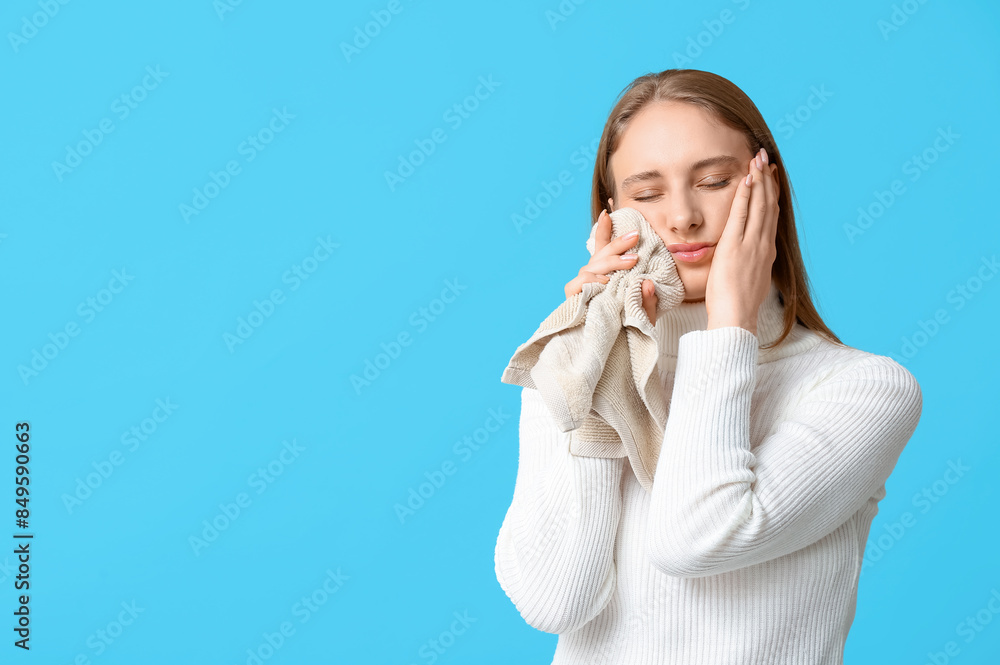 Beautiful young woman suffering from toothache with cold compress on blue background