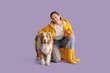 © Pixel-Shot - Pretty young woman in raincoat with cute Australian Shepherd dog on lilac background