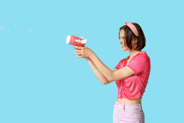 Poster - Teenage girl with soap bubble gun on blue background