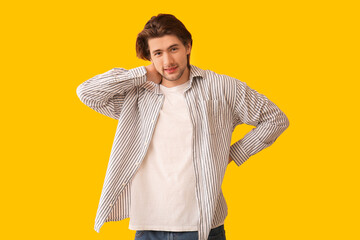 Wall Mural - Handsome young man suffering from neck pain on yellow background