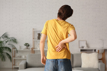 Wall Mural - Handsome young man suffering from back pain at home
