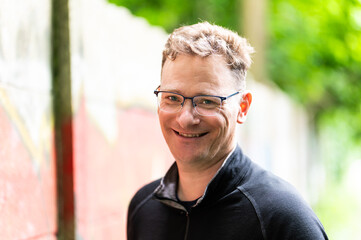 Outdoor portrait of a 45 yo white man with a green and red background, Jette, Belgium