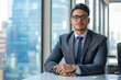 © koala studio - A businessman in a suit sits confidently at a desk in an office, looking directly at the camera