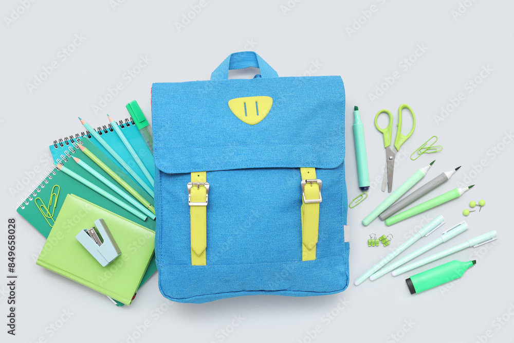 Composition with school backpack and different stationery on grey background