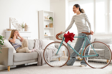 Wall Mural - Little girl receiving bicycle from her grandmother at home