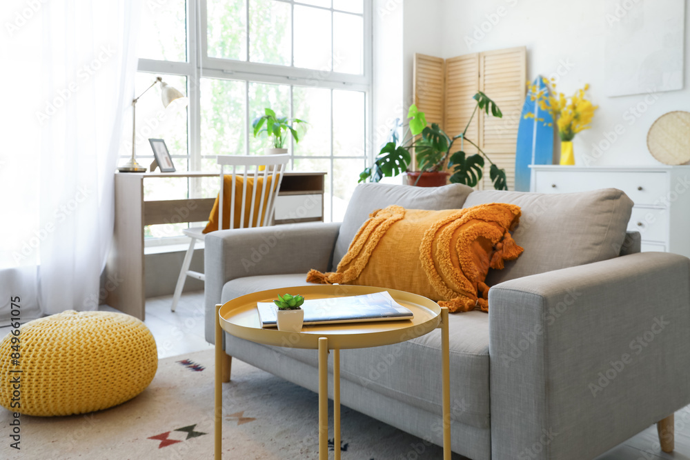 Interior of living room with sofa, workplace and surfboard