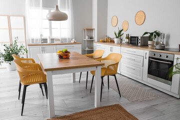 Wall Mural - Interior of modern kitchen with white counters, dining table, fruits, chairs and lamp