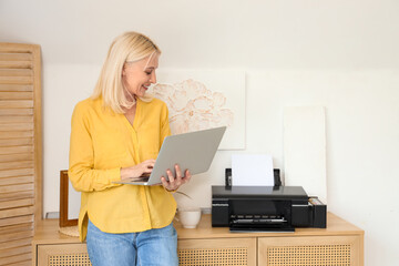 Canvas Print - Mature woman using laptop and printer at home