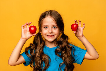 Wall Mural - Little girl holding fresh tomatoes in her hands on yellow background. Healthy food for children. Little girl with eco vegetables, isolated, space for text, concept organic food
