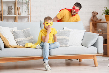 Wall Mural - Little boy with his father in superhero costumes playing at home