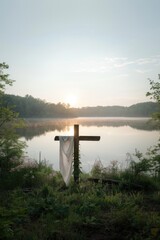 Canvas Print - Wooden cross with white cloth on the shore of a lake at sunrise.