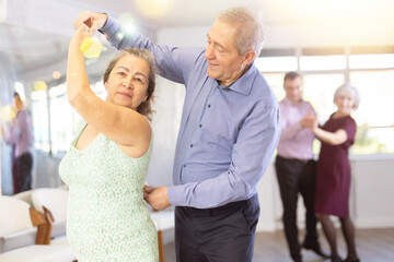 Wall Mural - Senior man and elderly woman are dancing classic version of waltz in couple during lesson at studio. Leisure activities and physical activity for positive people.