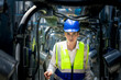 © ultramansk - A focused engineer wearing a safety vest and helmet inspects machinery in an industrial setting. The professional diligently checks equipment to ensure proper functionality and safety standards.