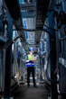 © ultramansk - An industrial worker in high-visibility gear and a blue helmet meticulously examines the intricate network of machinery. The engineer is dedicated to maintaining operational efficiency and safety.
