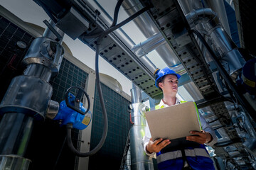 Wall Mural - An industrial worker in high-visibility gear and a blue helmet meticulously examines the intricate network of machinery. The engineer is dedicated to maintaining operational efficiency and safety.